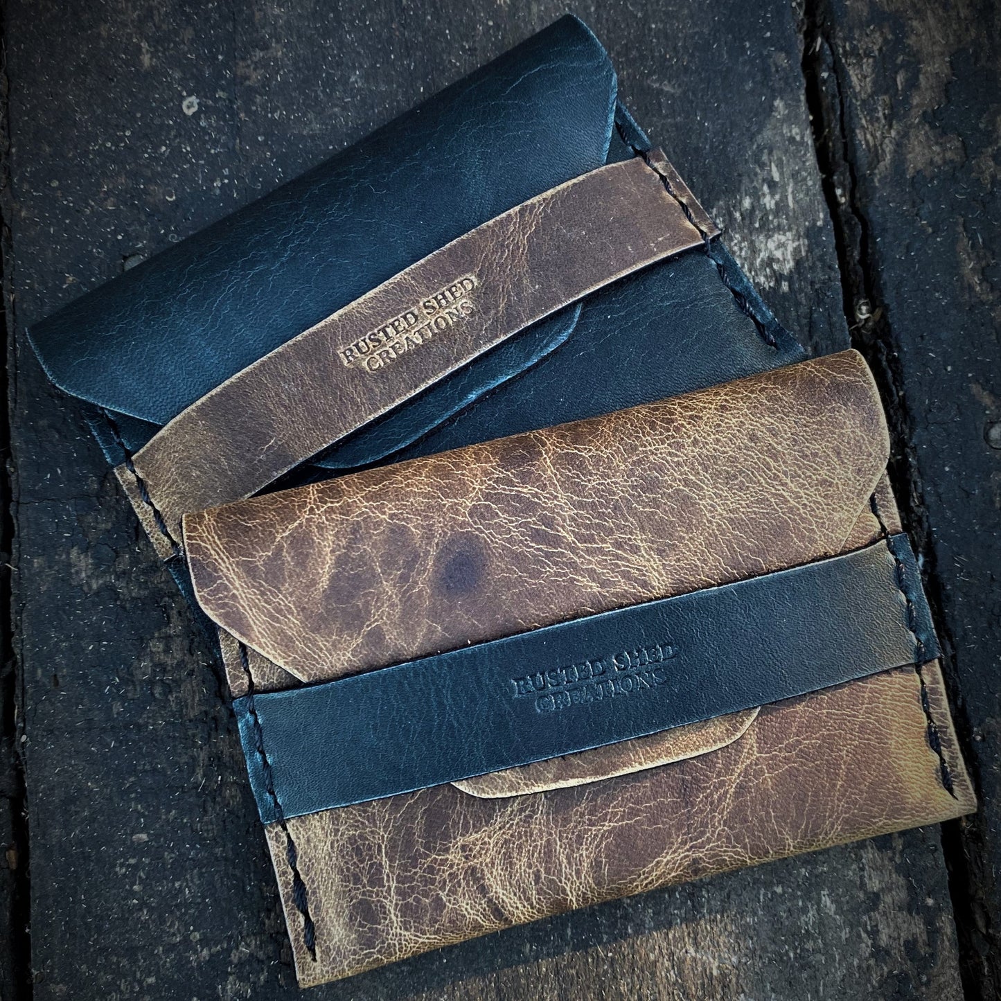 Three leather wallets in different colors on a textured surface