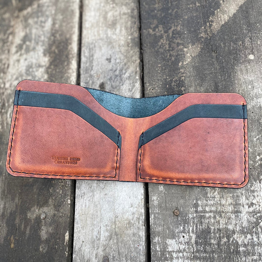 Brown leather wallet with black accents on a wooden surface
