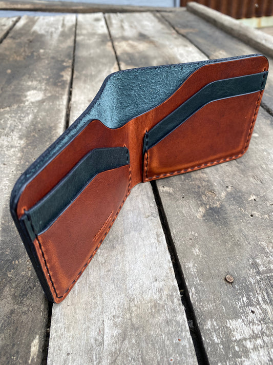 Brown leather wallet with black accents on a wooden surface