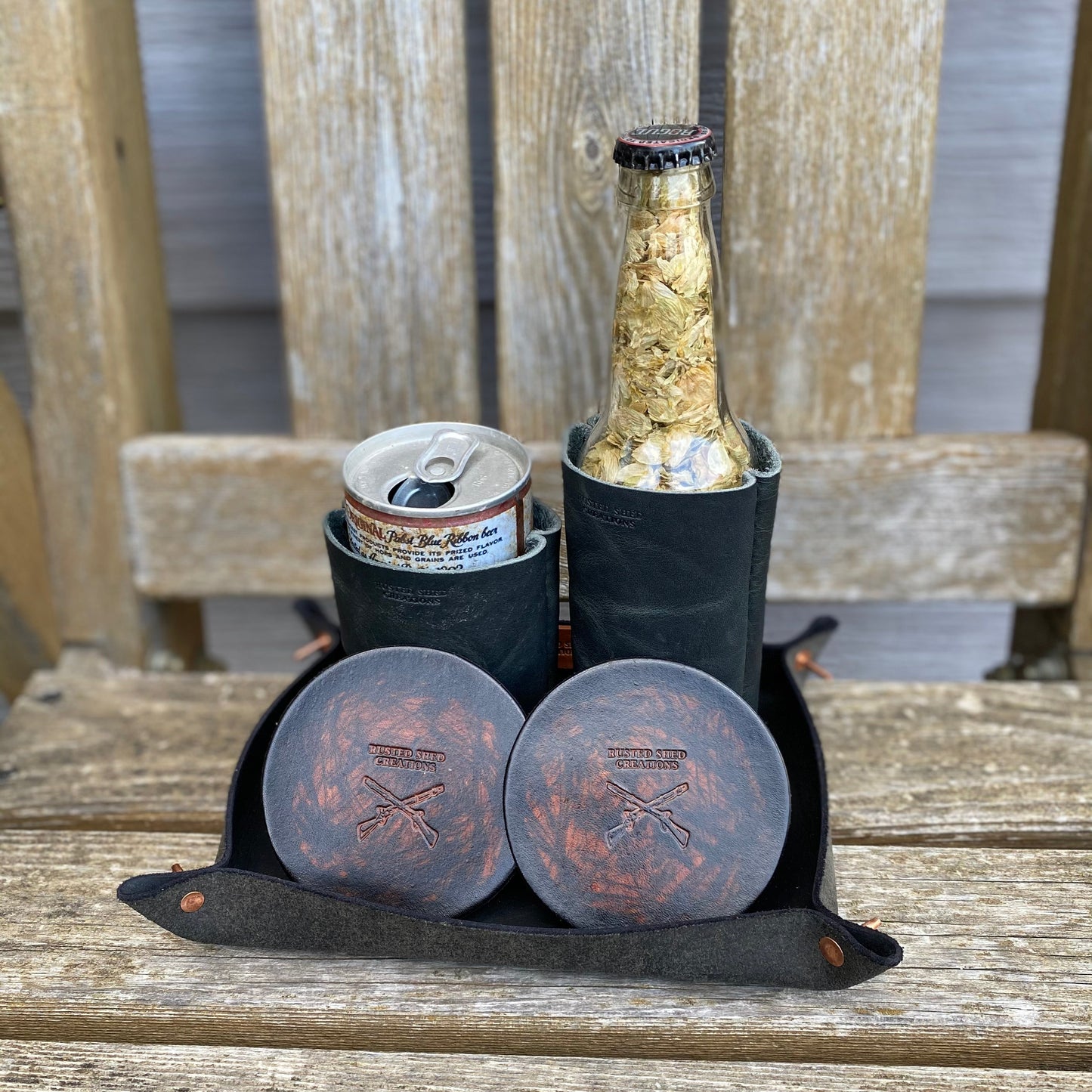 Black cooler bag with a bottle can koozie and two cans on a wooden surface